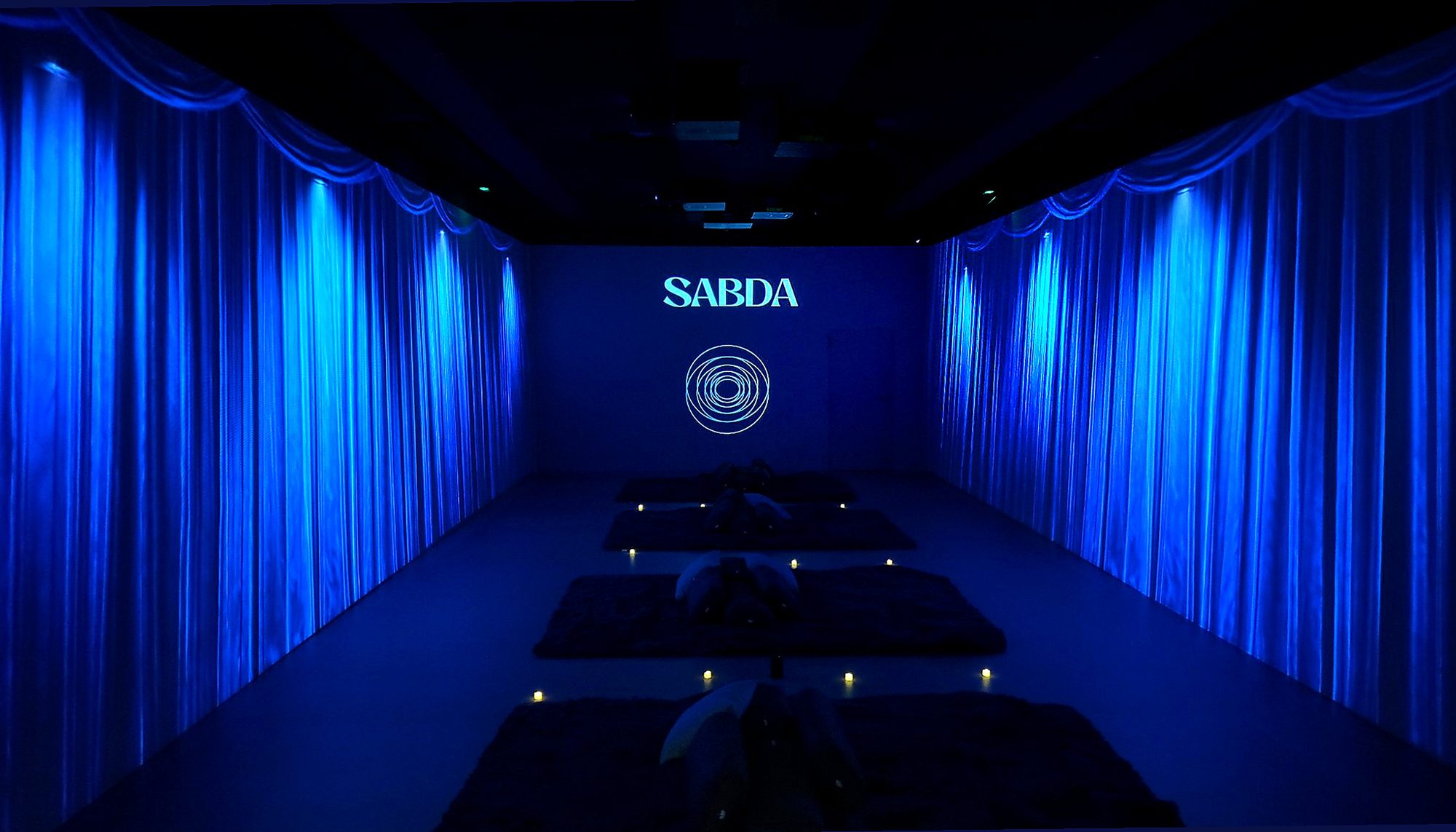 Sala immersiva de SABDA amb projeccions blaves 360 graus i estoretes de meditación a Barcelona