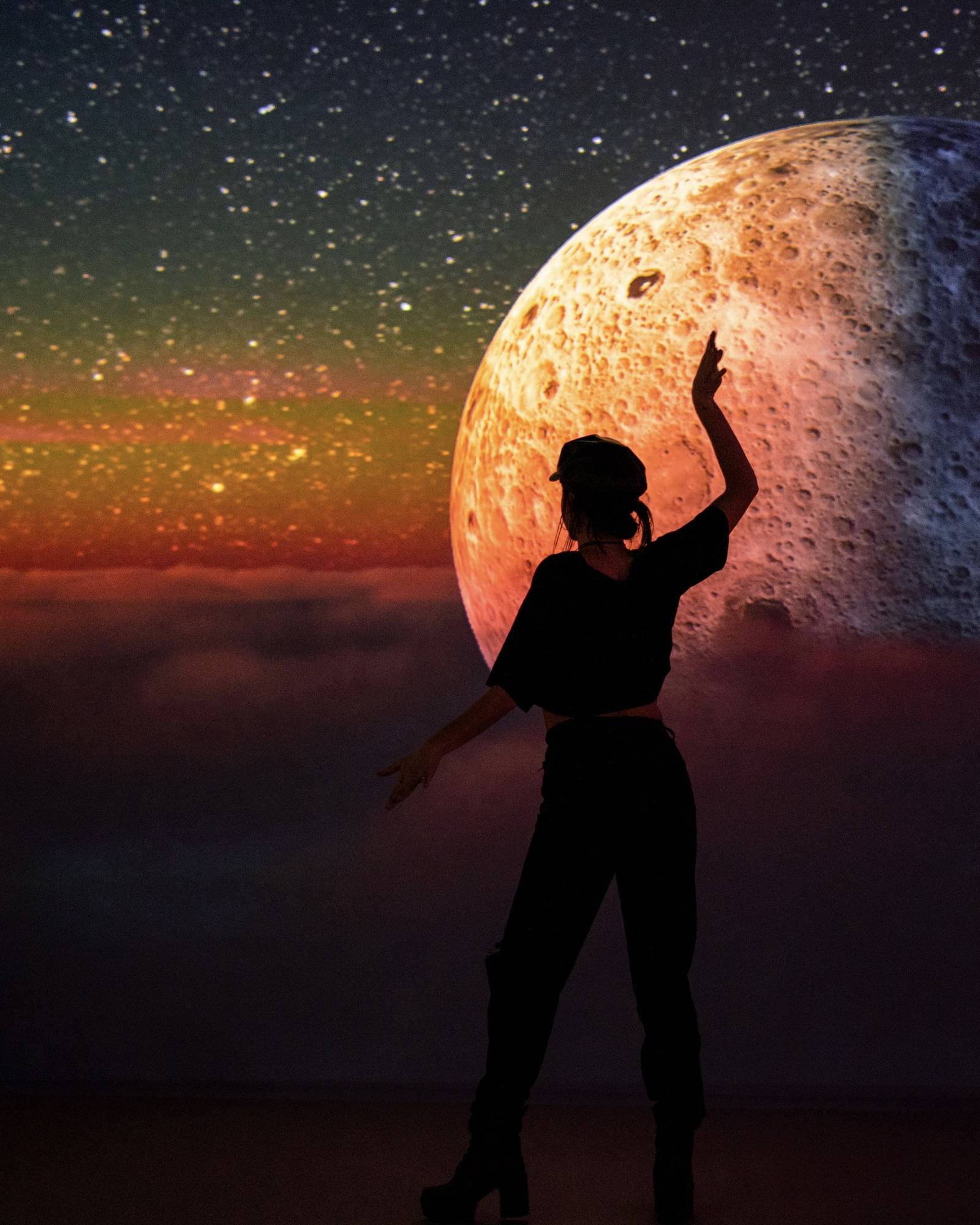 Bailarina junto a una luna proyectada en la sala 360 de SABDA, espacio para cumpleaños en Barcelona